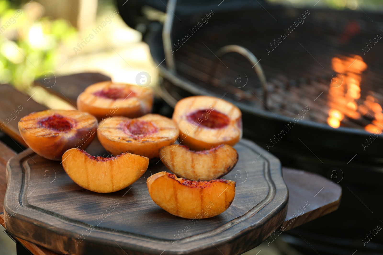 Photo of Delicious grilled peaches on wooden table outdoors, closeup