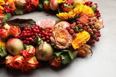 Beautiful autumnal wreath with flowers, berries and fruits on light grey background, closeup