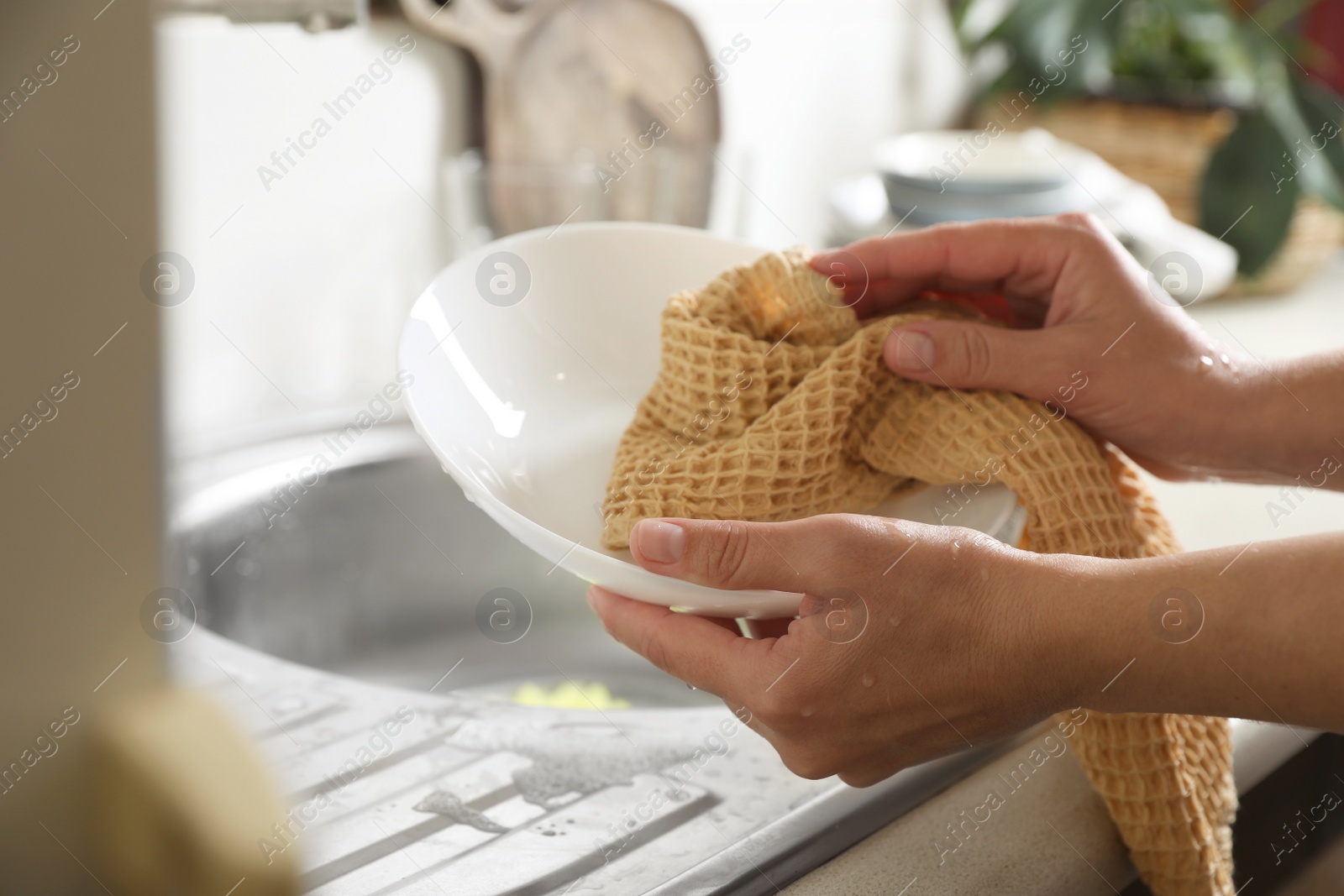 Photo of Woman wiping plate with towel in kitchen , closeup