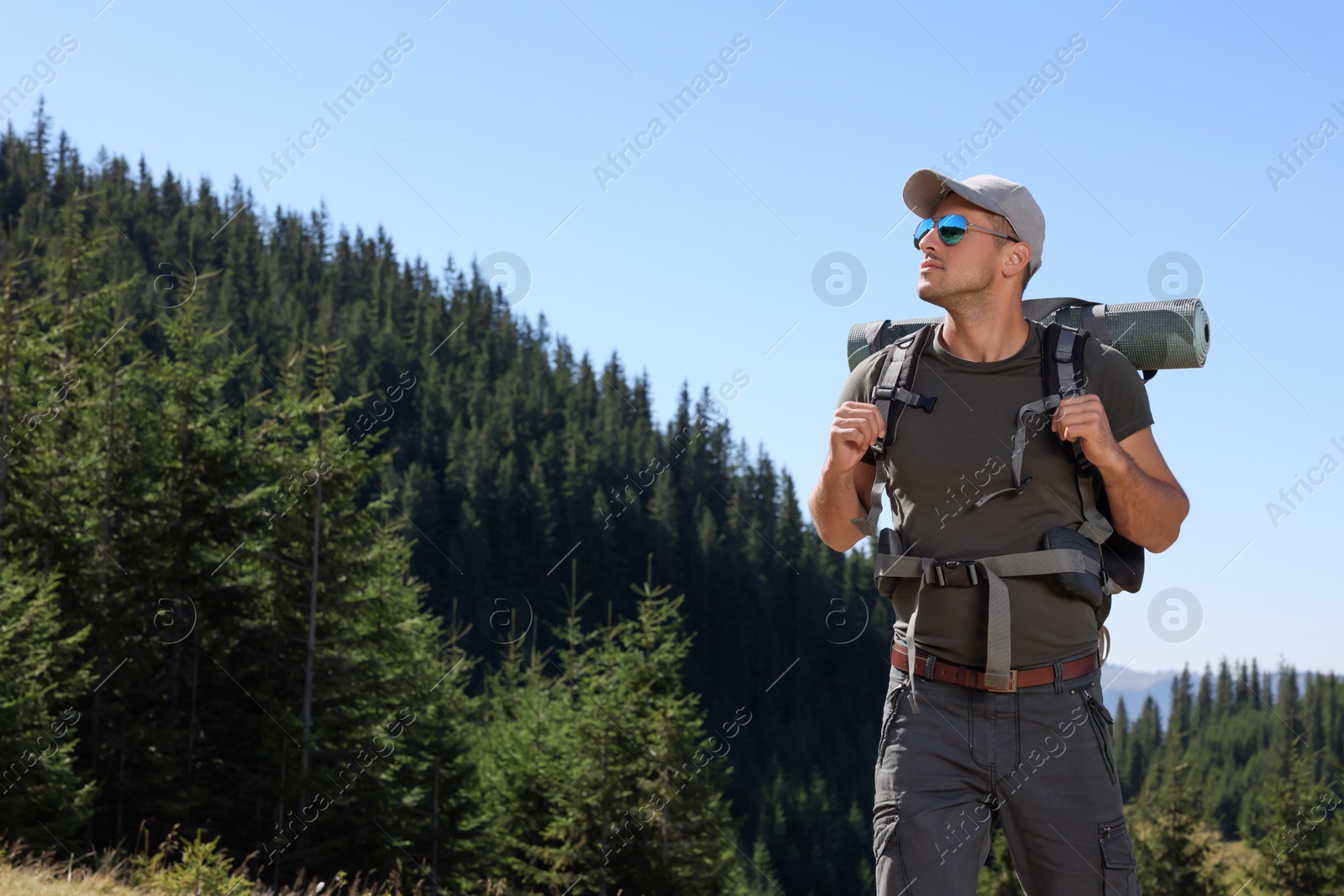 Photo of Man with backpack and sleeping mat in mountains. Space for text