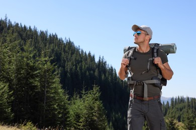 Photo of Man with backpack and sleeping mat in mountains. Space for text