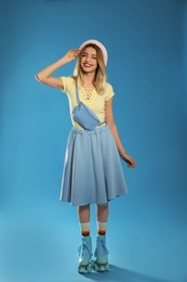 Young woman with retro roller skates on color background