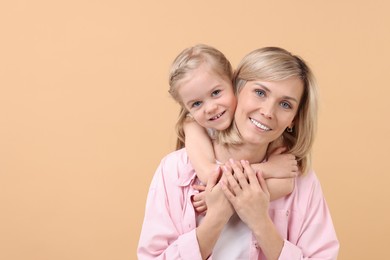 Family portrait of happy mother and daughter on beige background. Space for text