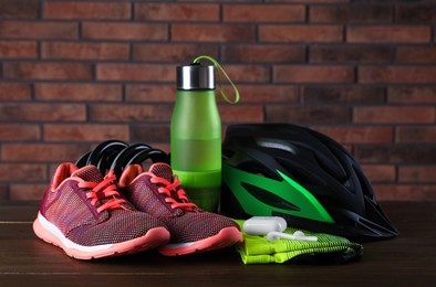 Photo of Different cycling accessories on wooden table against brick wall