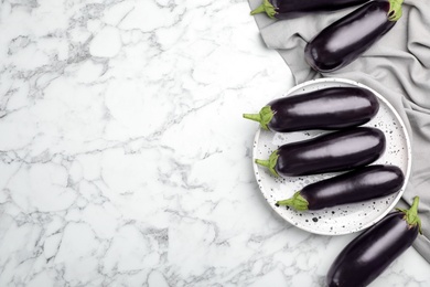 Photo of Raw ripe eggplants on marble background, top view