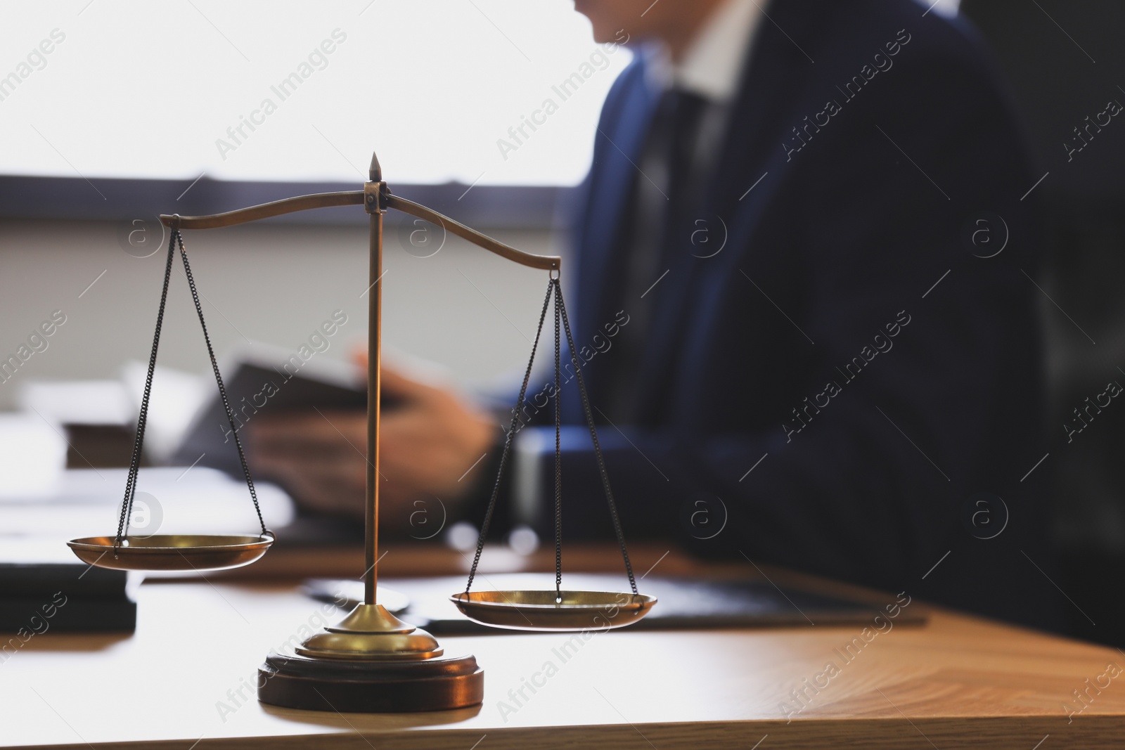 Photo of Scales of justice and blurred lawyer on background