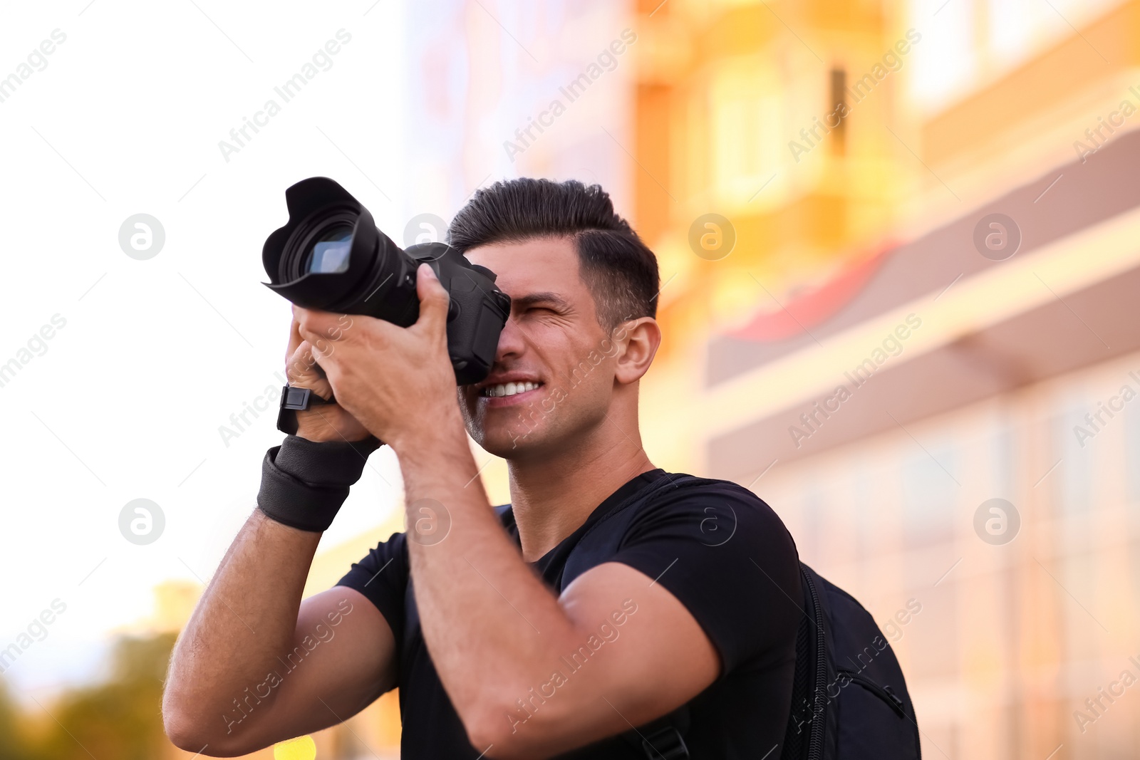 Photo of Photographer taking picture with professional camera on city street at sunset