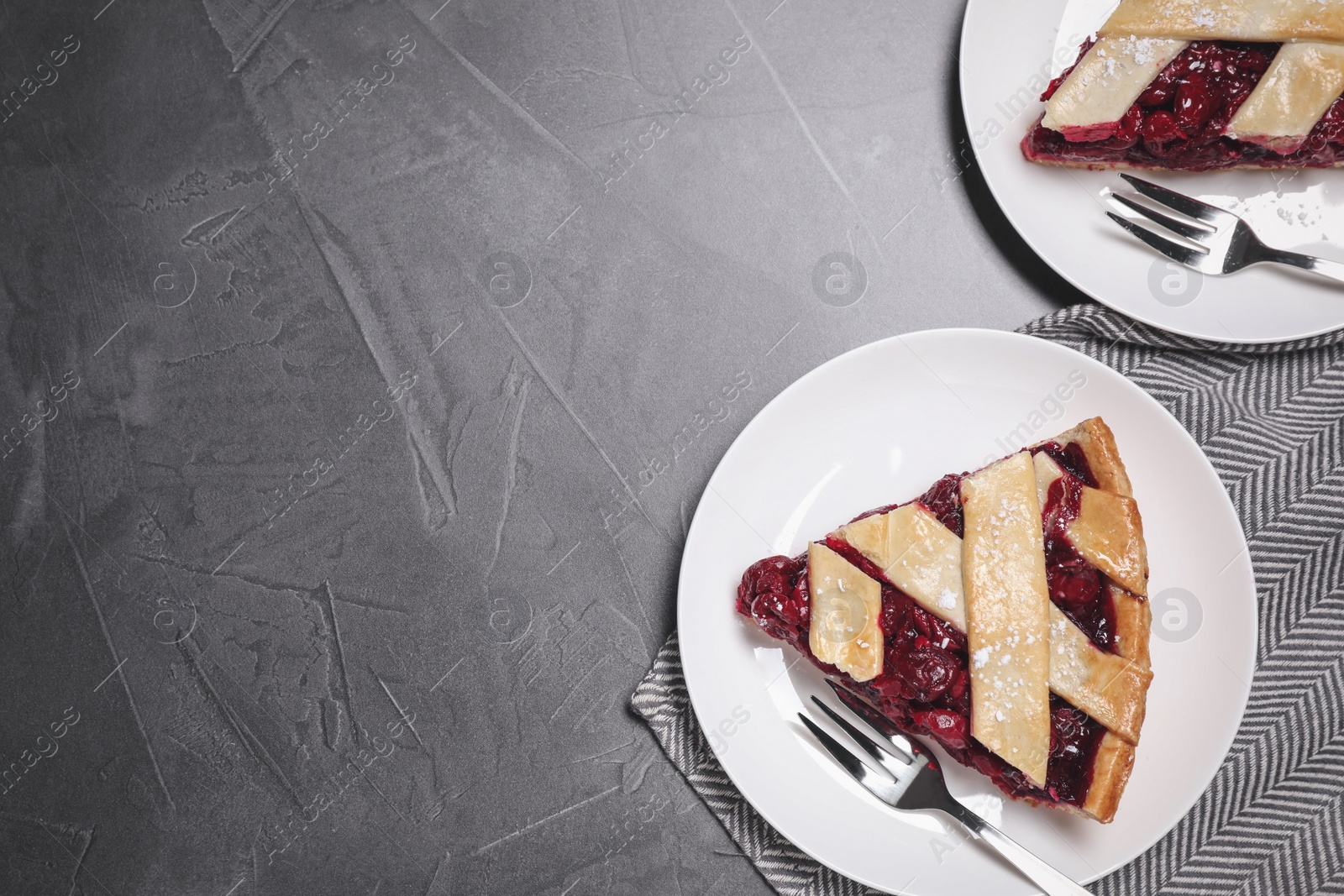 Photo of Slices of delicious fresh cherry pie served on grey table, flat lay. Space for text