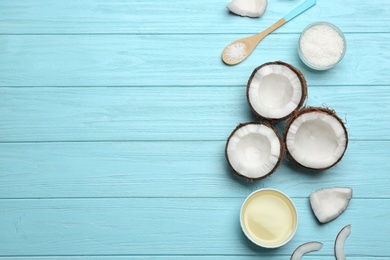 Bowl of natural organic oil and coconuts on blue wooden background, flat lay. Space for text