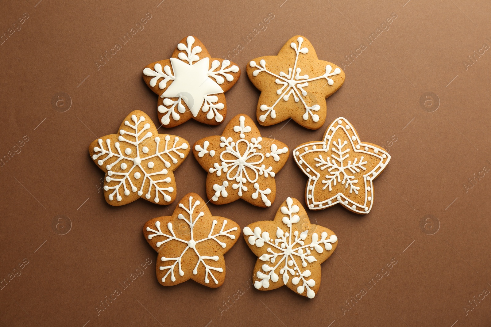 Photo of Tasty Christmas cookies with icing on brown background, flat lay