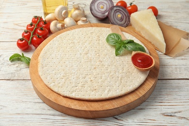 Photo of Base and ingredients for pizza on wooden table