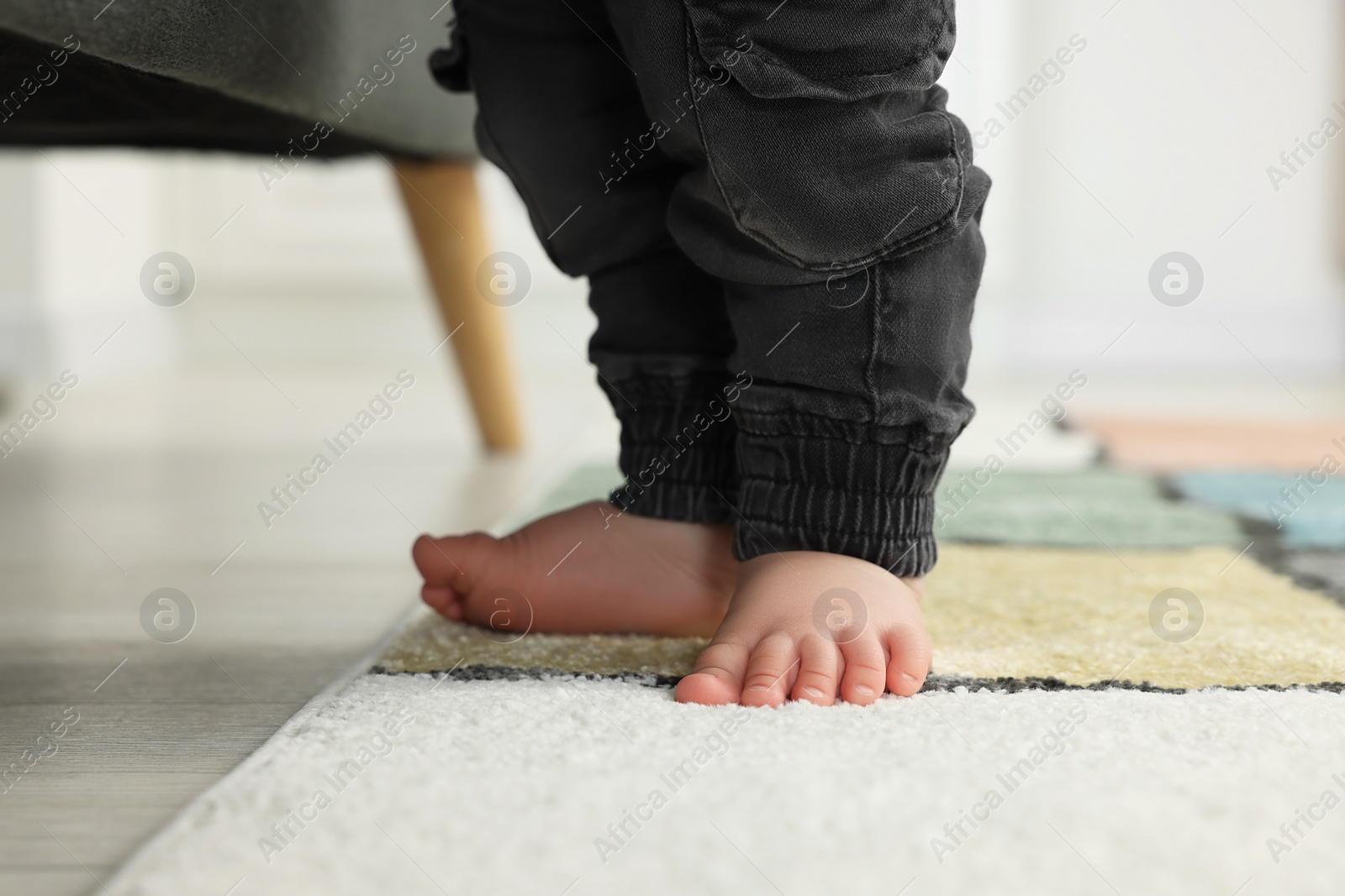 Photo of Baby walking on soft carpet, closeup view