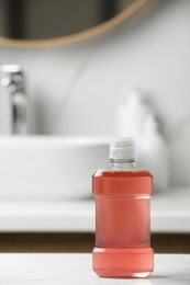 Photo of Bottle of mouthwash on white countertop in bathroom