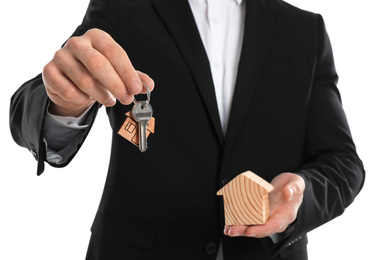 Photo of Real estate agent holding house figure and key on white background, closeup