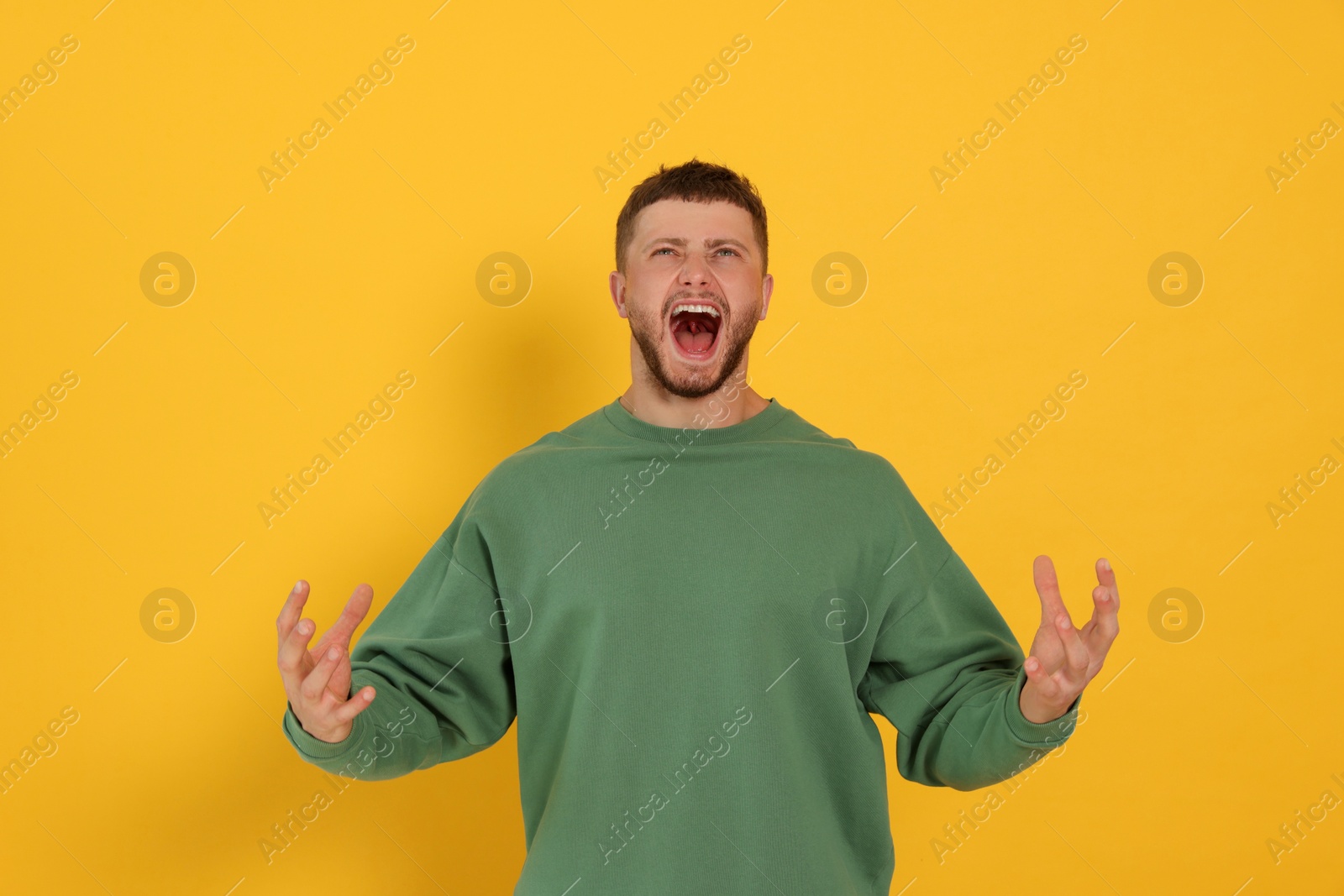 Photo of Aggressive young man shouting on orange background