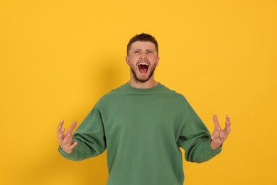 Photo of Aggressive young man shouting on orange background