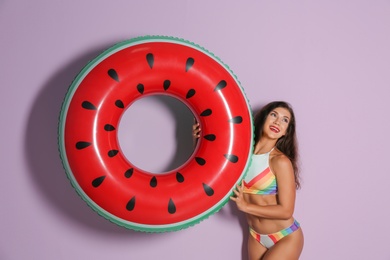 Beautiful young woman with inflatable ring on color background