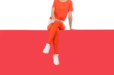 Woman wearing red tights and stylish shoes sitting on color background, closeup