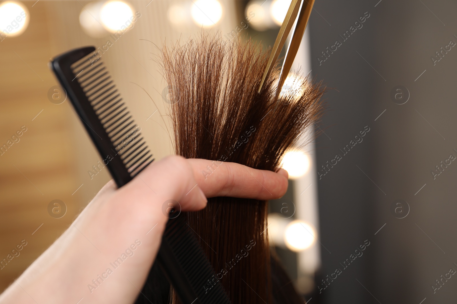 Photo of Hairdresser cutting client's hair with scissors in salon, closeup