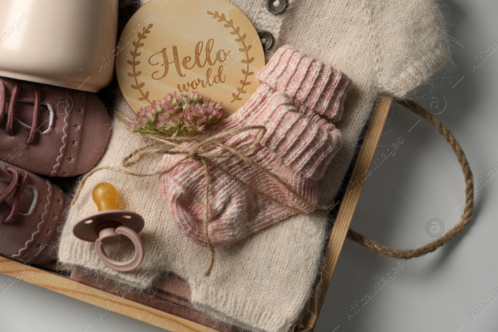 Photo of Box with baby clothes, shoes and accessories on light background, top view