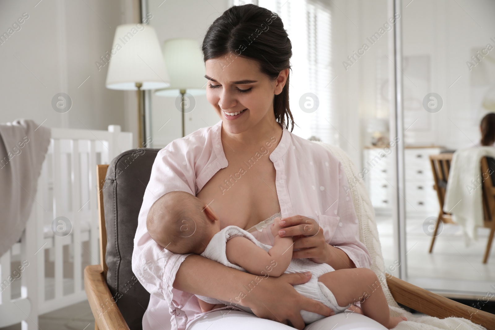 Photo of Young woman breastfeeding her little baby at home