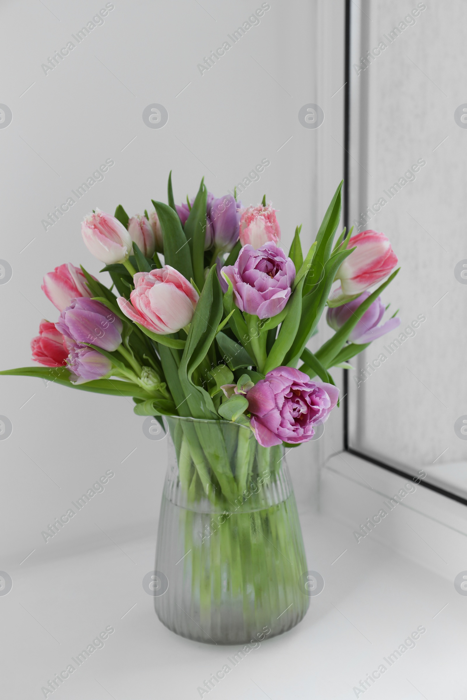 Photo of Beautiful bouquet of colorful tulip flowers on windowsill indoors