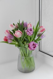 Photo of Beautiful bouquet of colorful tulip flowers on windowsill indoors