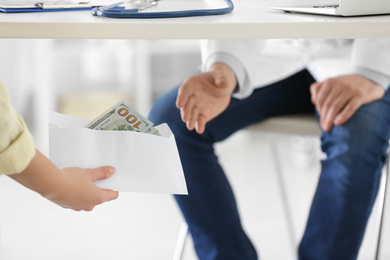 Patient giving bribe to doctor under table in clinic, closeup. Corrupted medicine