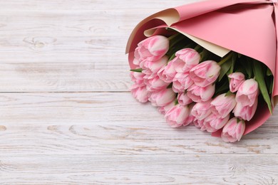 Photo of Beautiful bouquet of fresh pink tulips on white wooden table. Space for text