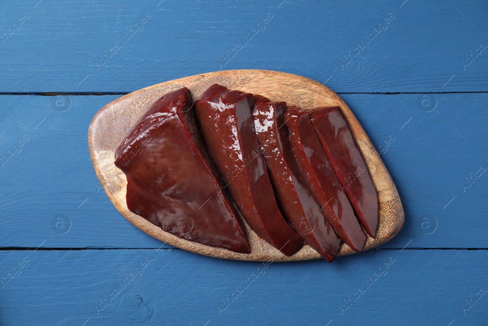 Photo of Cut raw beef liver on blue wooden table, top view