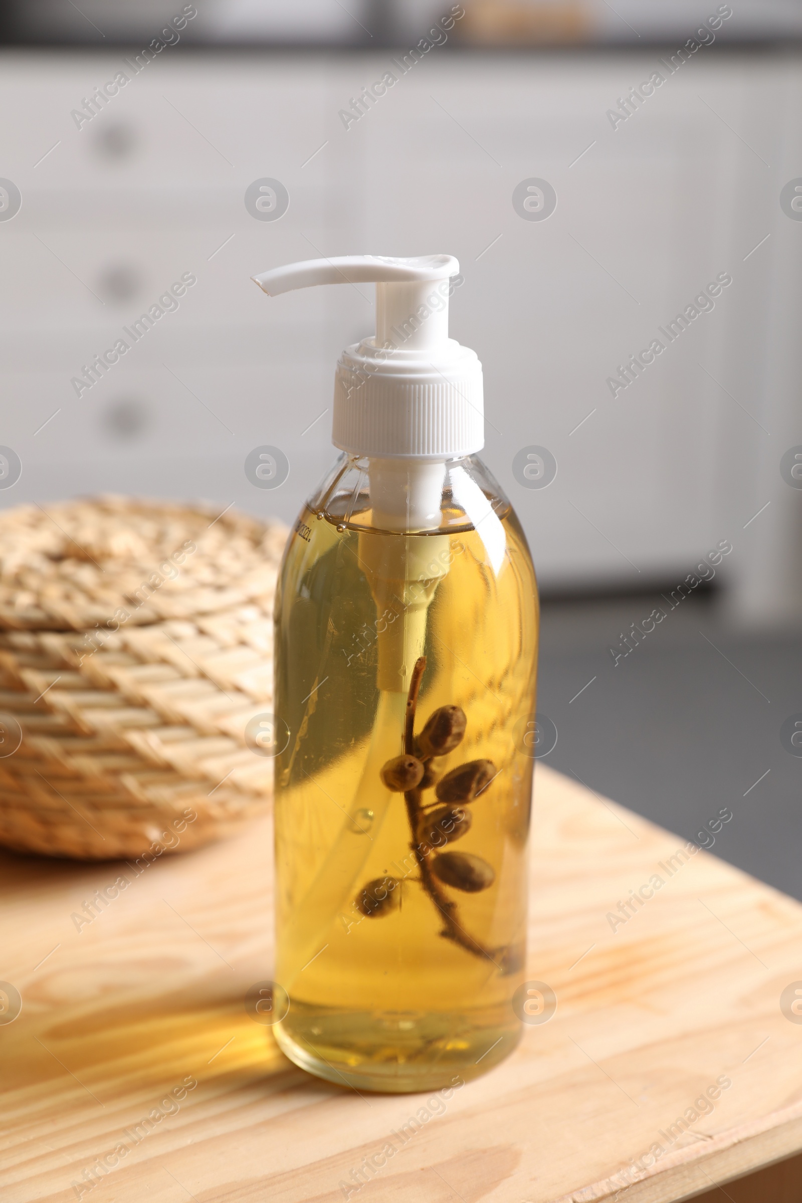Photo of Dispenser with liquid soap and wicker box on wooden table in bathroom