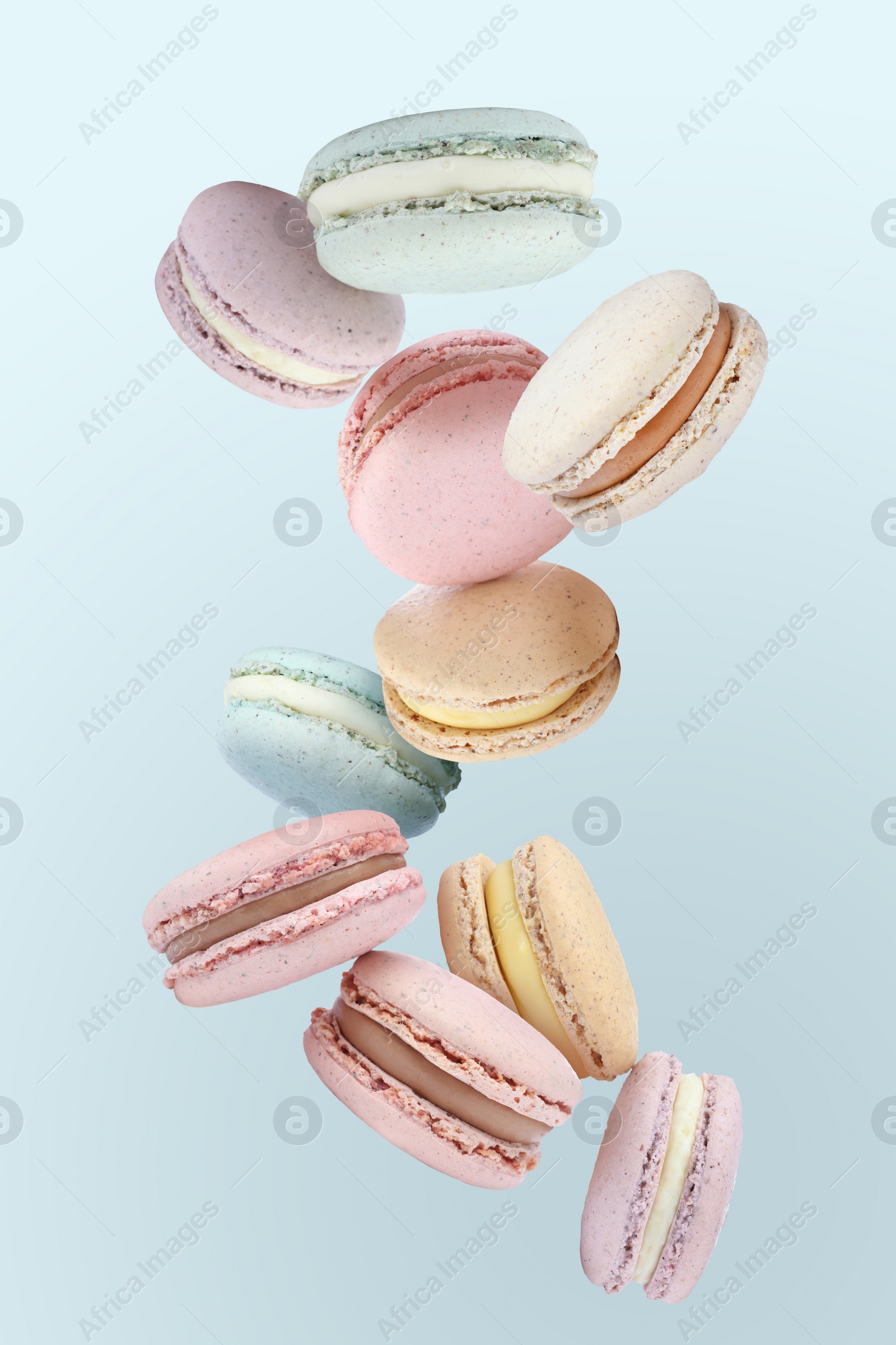 Image of Sweet delicious macarons flying on light blue background