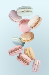 Image of Sweet delicious macarons flying on light blue background