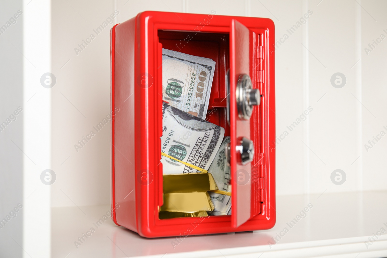 Open red steel safe with money and gold bars on shelf Photo of Open red steel safe with money and gold bars on shelf