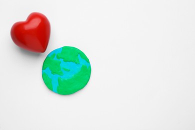 Photo of Model of planet and red heart on white background, top view with space for text. Earth Day