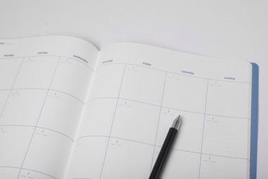 Photo of Open monthly planner and pen on white background, closeup