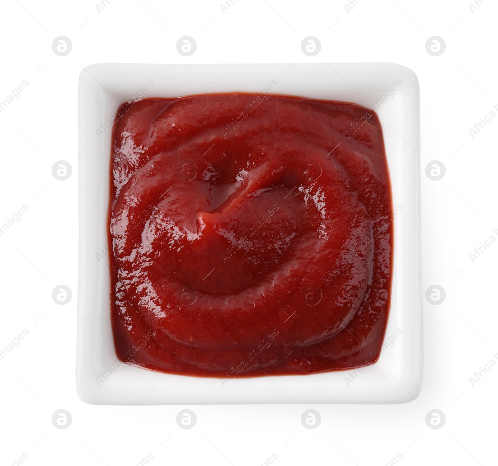 Photo of Tasty ketchup in bowl isolated on white, top view