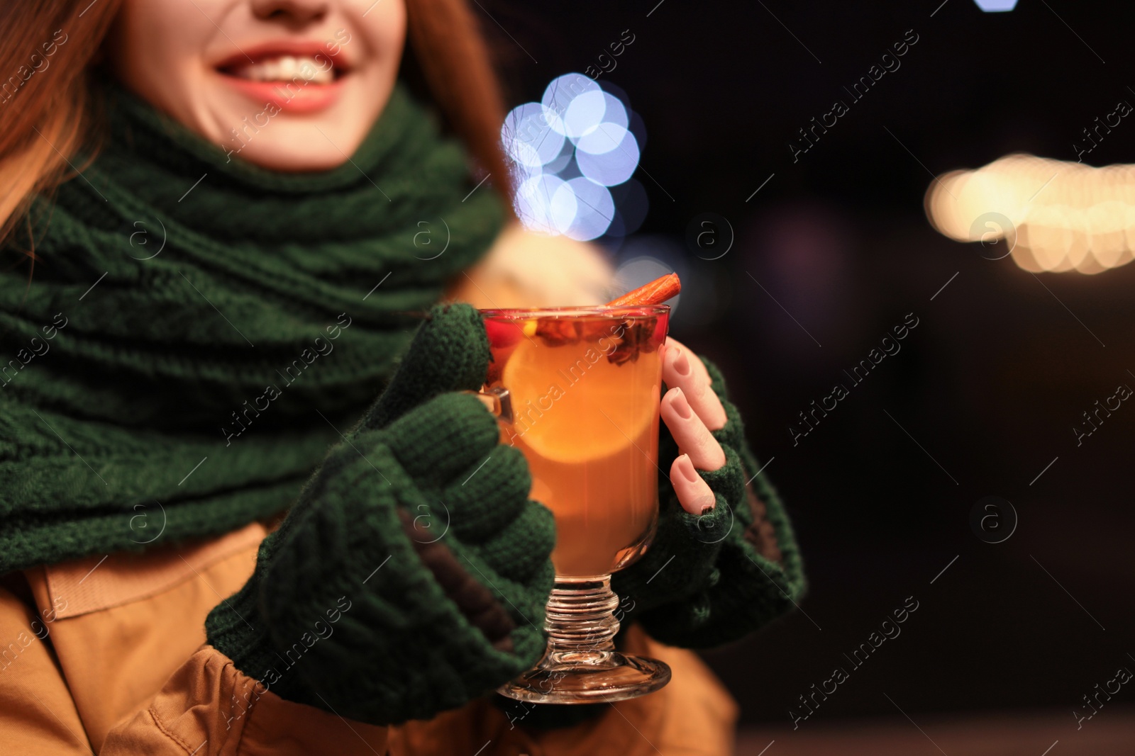 Photo of Woman with tasty mulled wine at winter fair, closeup