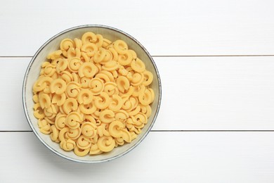 Photo of Raw dischi volanti pasta in bowl on white wooden table, top view. Space for text