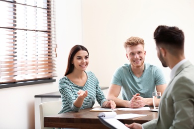 Photo of Insurance agent consulting young couple in office