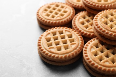 Photo of Tasty sandwich cookies with cream on grey table, closeup. Space for text