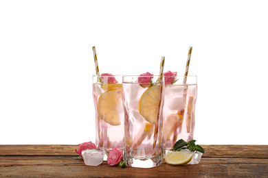 Photo of Delicious refreshing drink with rose flowers and lemon slices on wooden table against white background