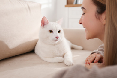 Photo of Young woman with her beautiful white cat at home. Fluffy pet