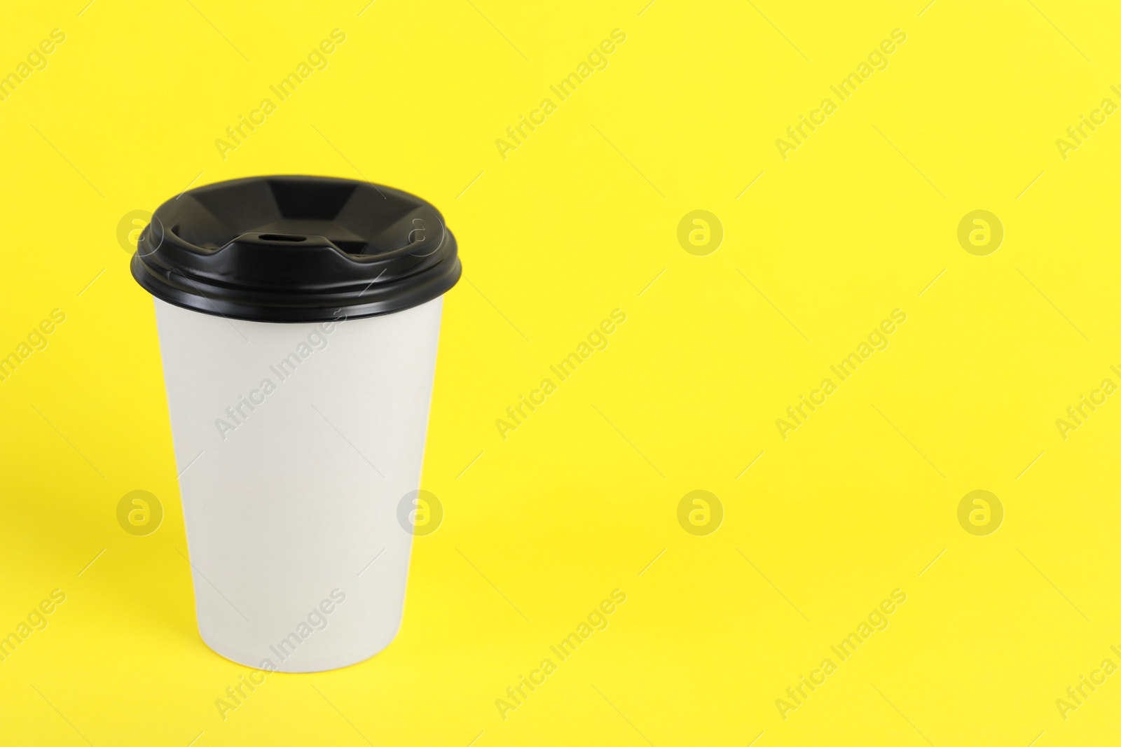 Photo of Paper cup with plastic lid on yellow background, space for text. Coffee to go