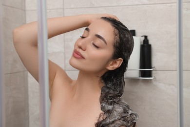 Photo of Beautiful woman washing hair in shower stall