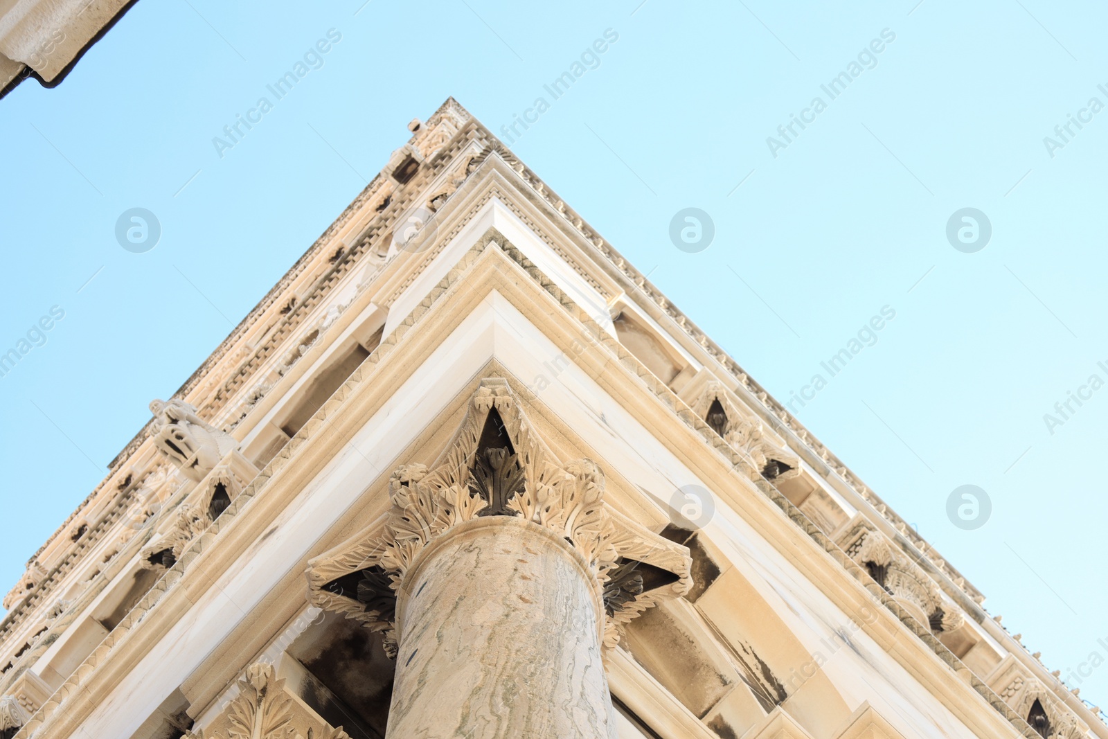 Photo of Facade of beautiful old building against light blue sky, low angle view