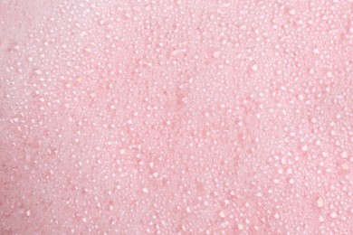 Photo of White fluffy foam on pink background, top view