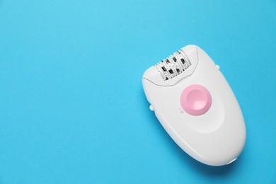Modern epilator on light blue background, top view. Space for text