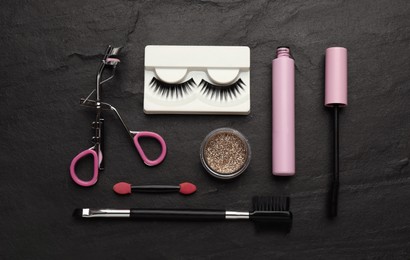 Photo of Flat lay composition with eyelash curler, makeup products and accessories on black table