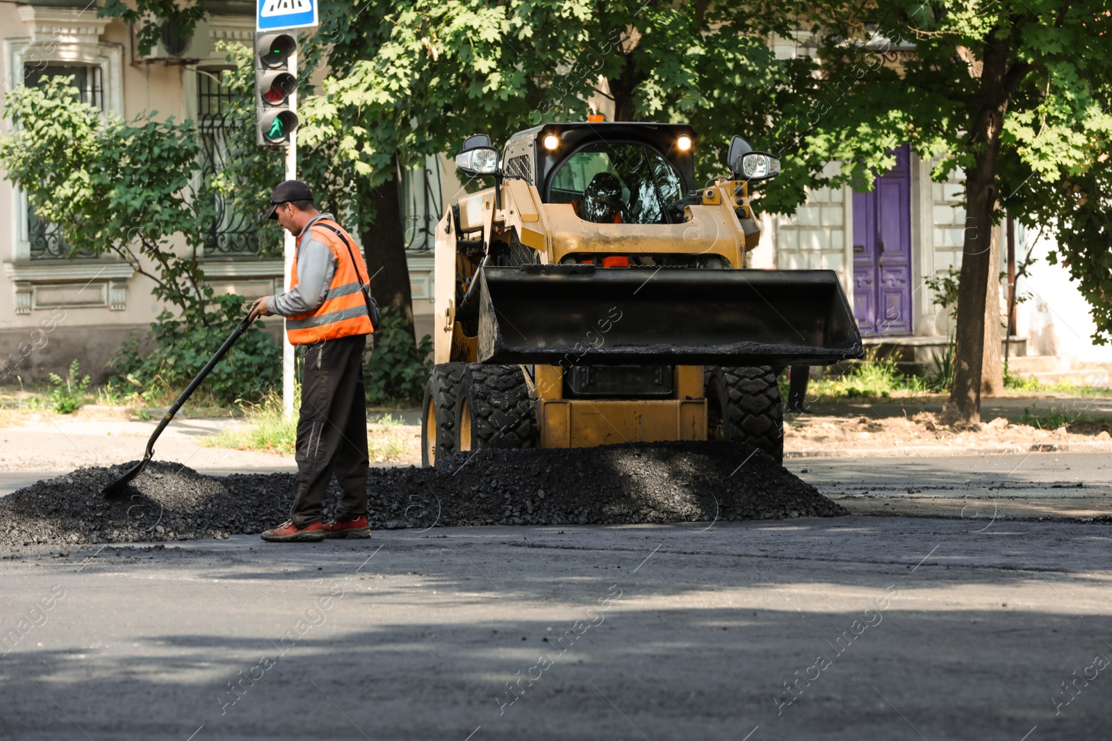 Photo of MYKOLAIV, UKRAINE - AUGUST 05, 2021: Worker laying new asphalt on city street. Road repair service